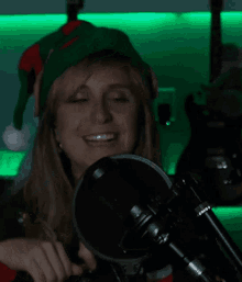 a woman wearing an elf hat is smiling behind a microphone