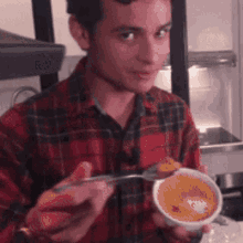 a man in a plaid shirt is holding a bowl and spoon
