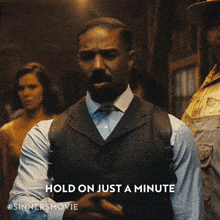 a man in a suit says hold on just a minute on a poster