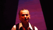 a man in a white shirt and black vest stands in front of a screen