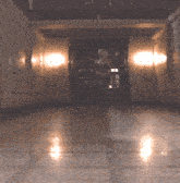 a woman walking down a hallway with a few lights on the walls