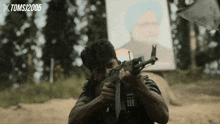 a man holding a gun in front of a poster that says tomsj 2005