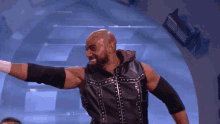 a wrestler in a black vest with studs on it is smiling