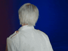 a person with white hair is wearing a white jacket with gold buttons