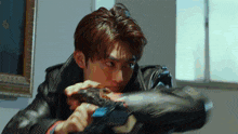 a man in a leather jacket is holding a gun in his right hand