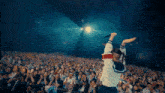 a person holding a microphone in front of a crowd that says ' nirvana ' on their jacket