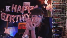 a girl is sitting in front of a sign that says k happy birthday