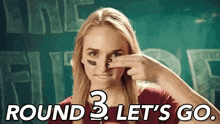 a woman is covering her nose with her hand and says `` round 3 let 's go '' .