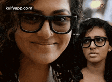 a woman wearing glasses and a nose ring is smiling and looking at the camera