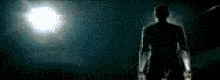 a silhouette of a man standing in front of a full moon