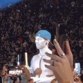 a man in a blue hat is being photographed by a woman with yellow nails