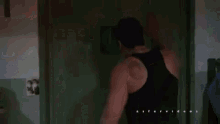 a man is standing in front of a door in a dark room and talking on a cell phone .