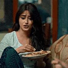 a woman is sitting on a couch eating food from a plate