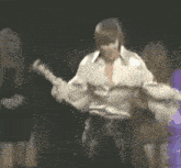 a man in a white shirt is playing a guitar in a dark room