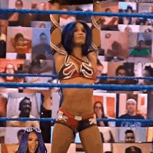 a woman in a bikini is standing in a wrestling ring with her hands in the air .
