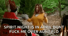 a woman in a yellow sweater is standing next to a man in a red robe in the woods .