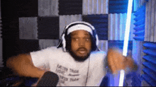 a man wearing headphones and a headband is sitting in a room holding a light saber .