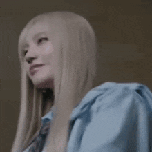 a woman with long blonde hair is wearing a blue shirt and smiling .