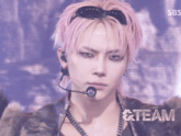 a man with pink hair is wearing sunglasses and a microphone and the word team is behind him