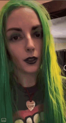 a woman with green hair is wearing a necklace with a heart that says jenny on it