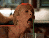 a woman drinking through a green straw with her tongue sticking out