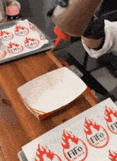 a person is pouring hot sauce into a cardboard container that says fifo on it
