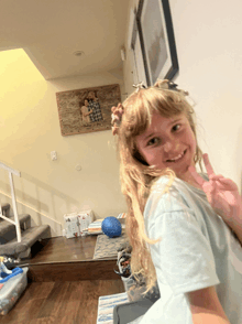 a little girl giving a peace sign in front of a picture of a family