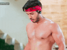 a shirtless man wearing a red headband and headphones is standing in a room .