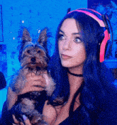 a woman with blue hair holds a small dog