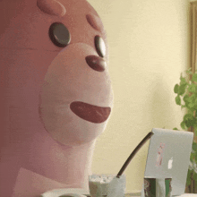a pink teddy bear is sitting in front of a laptop