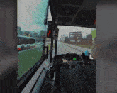 a man is driving a bus with a green screen on the steering wheel