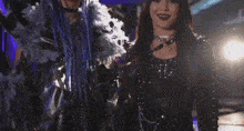 a woman with blue hair is standing next to a woman with dark hair