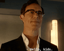 a man wearing glasses and a suit says hello kids on the bottom