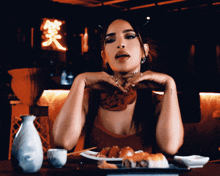 a woman is sitting at a table with a plate of sushi and a bottle of sake