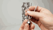 a person is holding a metal ball and a metal stick in their hands