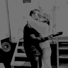 a black and white photo of a man and woman hugging each other .