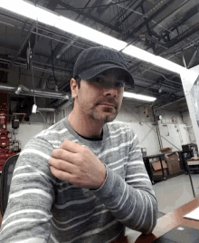 a man wearing a hat and a striped sweater is sitting at a desk