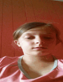 a young girl in a pink shirt looks at the camera with her eyes closed