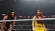 two women are standing in a wrestling ring with the word raw written on the ropes
