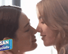 two women are kissing each other 's noses in front of a sign that says ' jan ' on it .