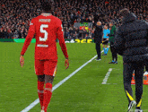 a soccer player wearing a red jersey with the number 5 on the back