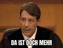 a man in a judge 's robe is sitting in a courtroom and says da ist doch mehr