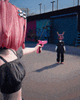 a girl with pink hair is pointing a pink gun at a boy with bunny ears
