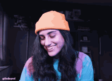 a woman wearing an orange beanie and a blue shirt with the words gifsdayrol on the bottom right