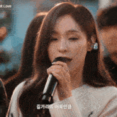 a woman singing into a microphone with the word love on the bottom right