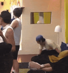 a group of people are standing around a couch in a room with a mirror on the wall