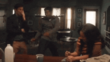a man and a woman are dancing in a living room while a woman is writing on a piece of paper .