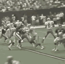 a group of football players are playing a game on a field . one of the players has the number 8 on his jersey .