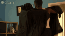 a man and woman are standing in a room with the word gem on the wall