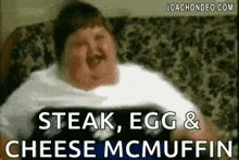 a fat man is sitting on a couch with the words `` steak , egg & cheese mcmuffins '' written on it .